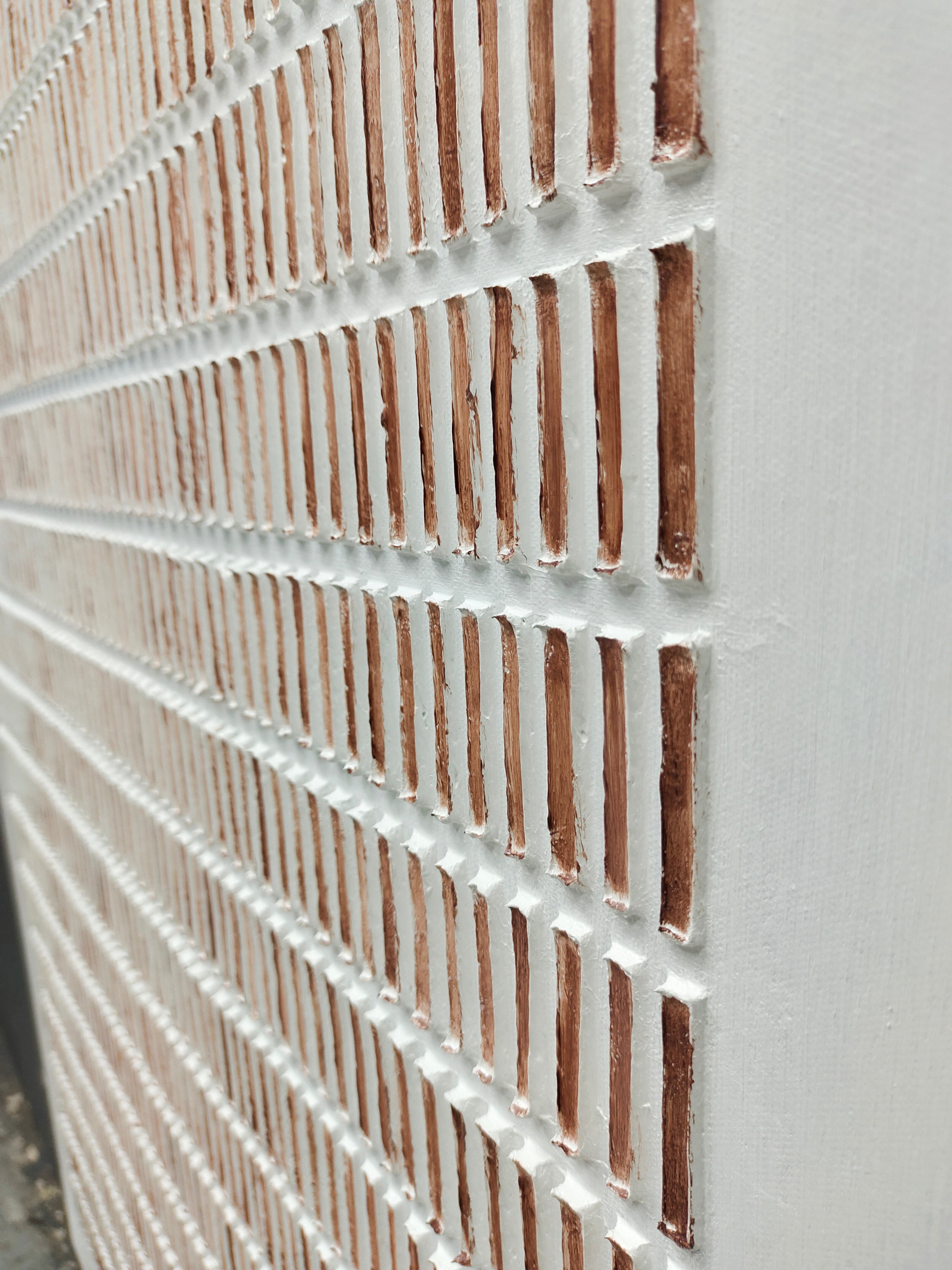 Close-up of a textured wall art with horizontal lines and a white background