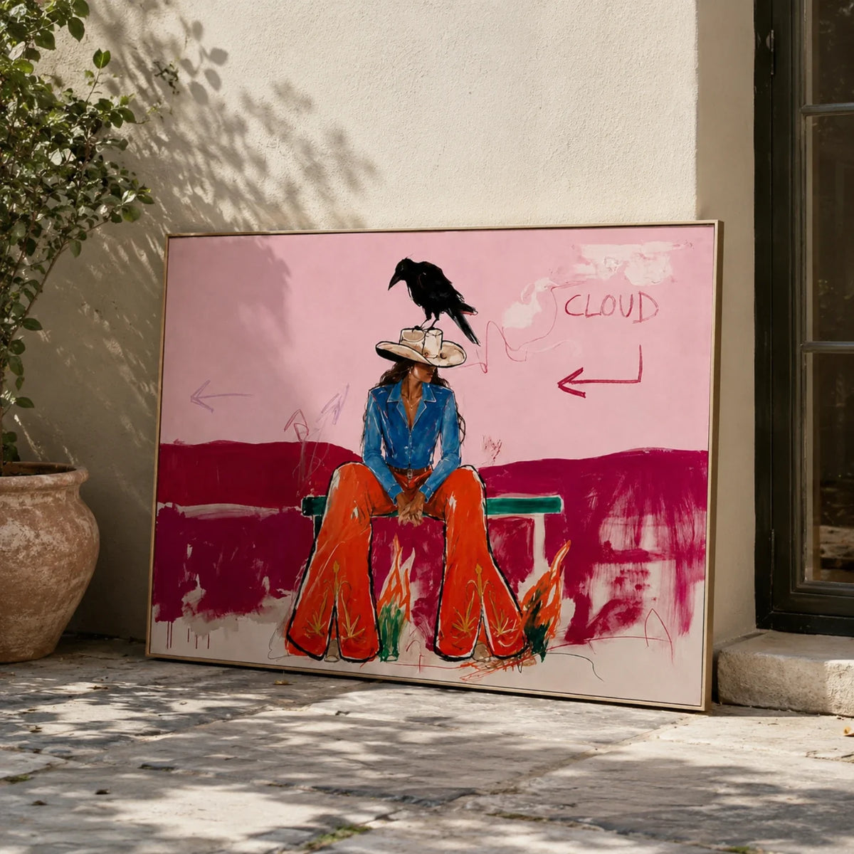 Trendy pink Southwestern cowgirl canvas painting displayed above a velvet couch in a modern boho living room