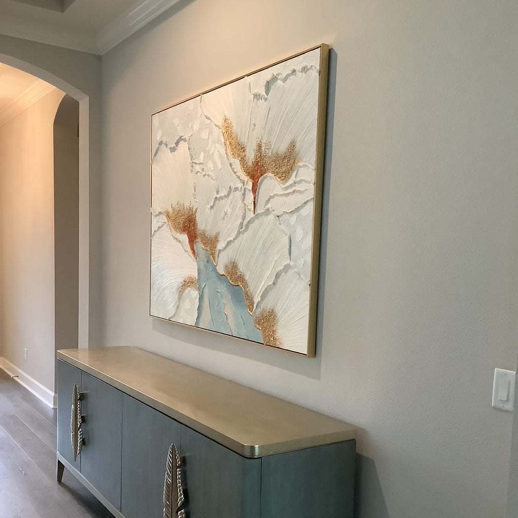A gold floral textured wall art piece hangs above the console table in the entryway.