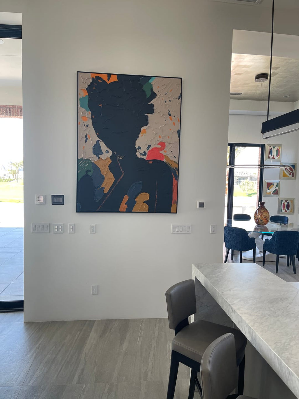 A black abstract portrait plaster wall art painting hangs on the wall of the dining room.