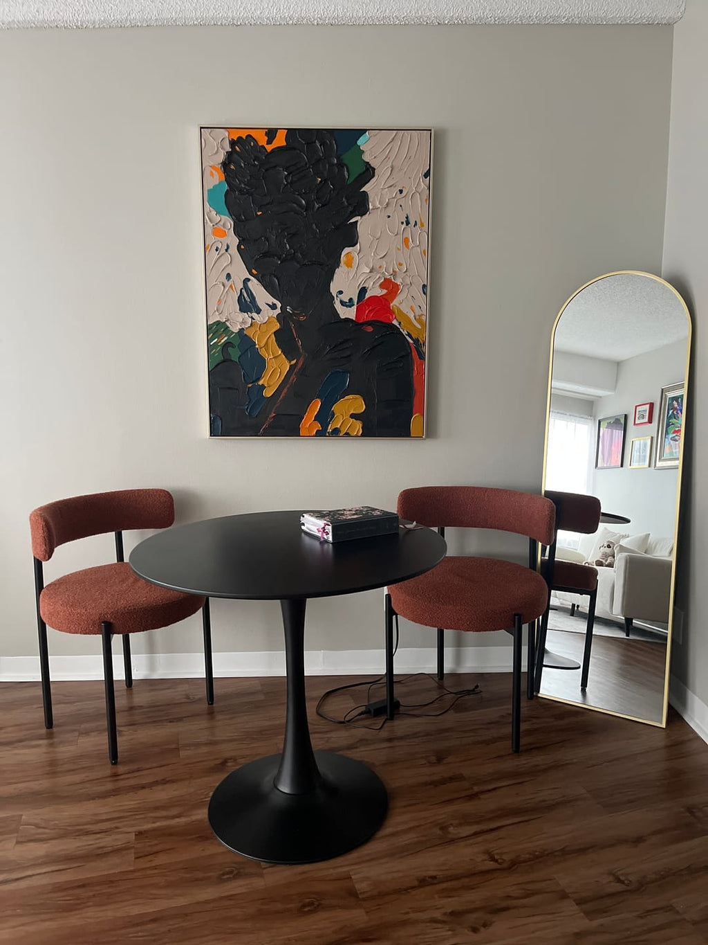 A black abstract people plaster wall art painting hangs in the dining room.