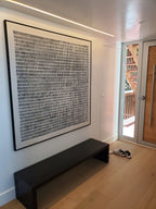 A large framed black and white abstract art print hangs on a porch stool in a modern entryway.
