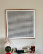 A large framed minimalist square art print featuring a black and white grid pattern above a console table.