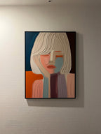 A framed abstract portrait painting of a woman with stylized geometric shapes in orange, blue, beige, and purple, hanging on a living room wall.