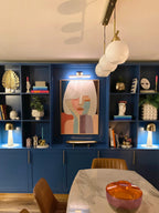 A large, colorful abstract portrait painting hangs in the center of a modern dining room.