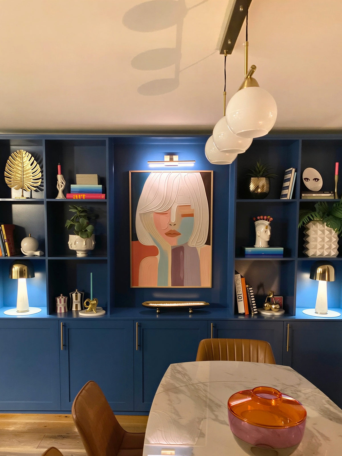 A large, colorful abstract portrait painting hangs in the center of a modern dining room.