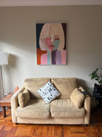 Modern abstract face wall art styled above a contemporary minimalist sofa in a luxury living room