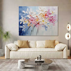 Heavy textured colorful abstract flower canvas artwork styled above a neutral linen sofa in a bright modern living room