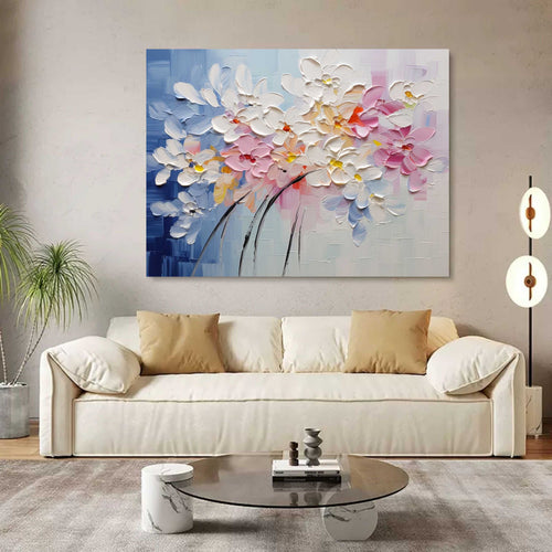 Heavy textured colorful abstract flower canvas artwork styled above a neutral linen sofa in a bright modern living room