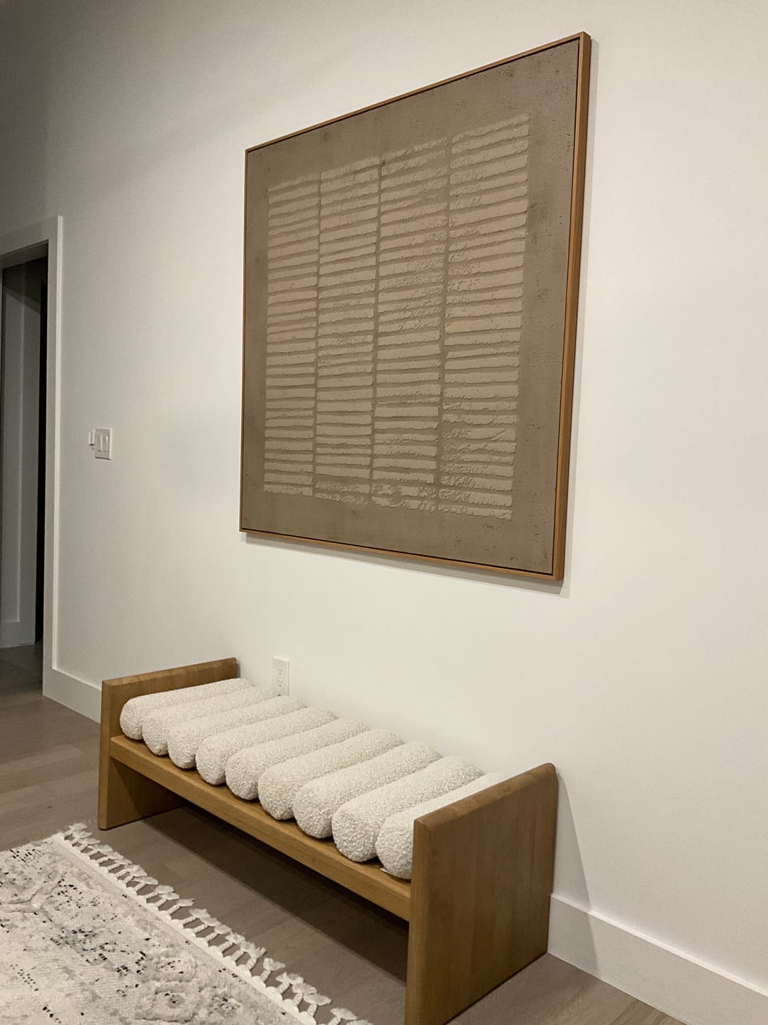A large, square framed abstract art painting hanging above the entryway bench is the perfect decoration for the entryway.