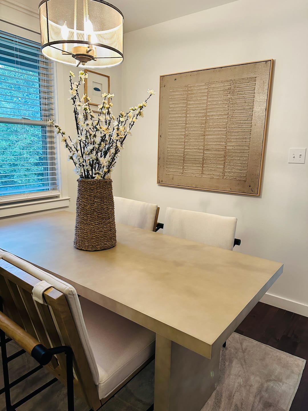 A large beige wabi-sabi framed artwork hangs above the dining table in the dining room.