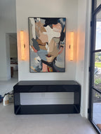 An abstract, colorful, textured portrait painting hangs above a stool in the entryway.