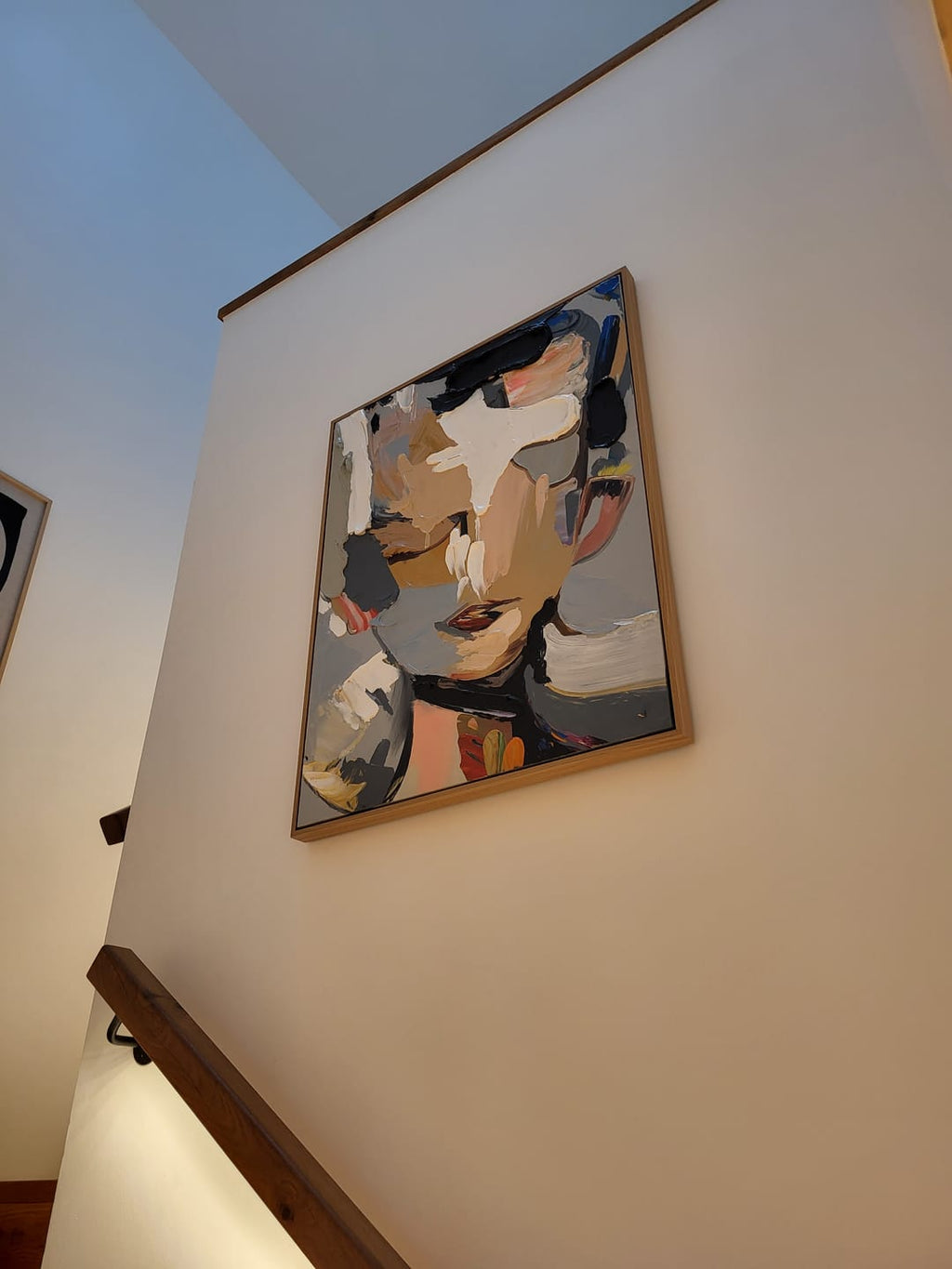 A white abstract figure plaster wall art painting hangs on the staircase wall.