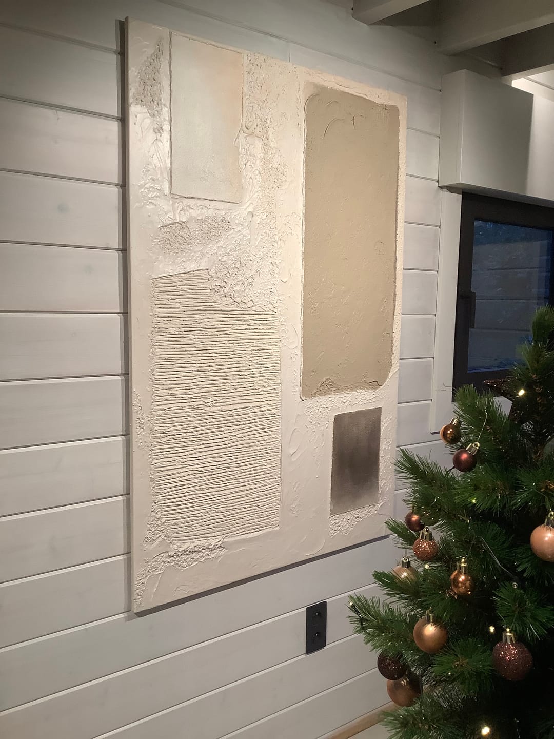 A large abstract canvas wall art piece with textured cream, beige, and gray mounted on a living room wall.
