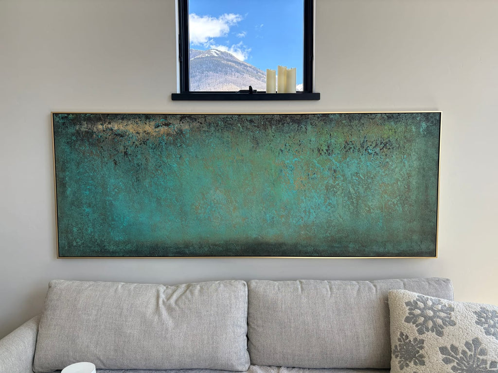 Large horizontal green abstract canvas artwork beautifully framed and hung above a modern rustic living room sofa.