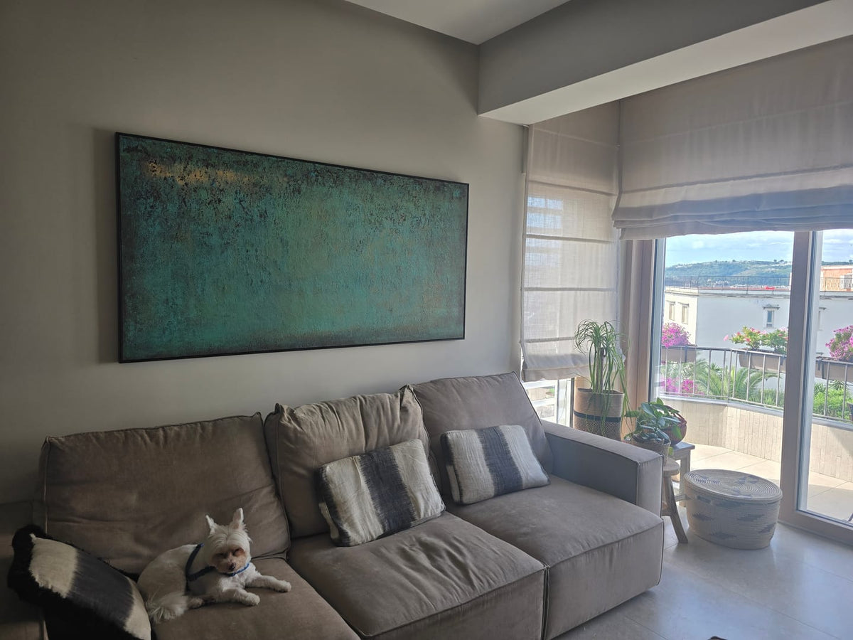 A large abstract teal and green wall art painting above a long sofa for a modern living room.