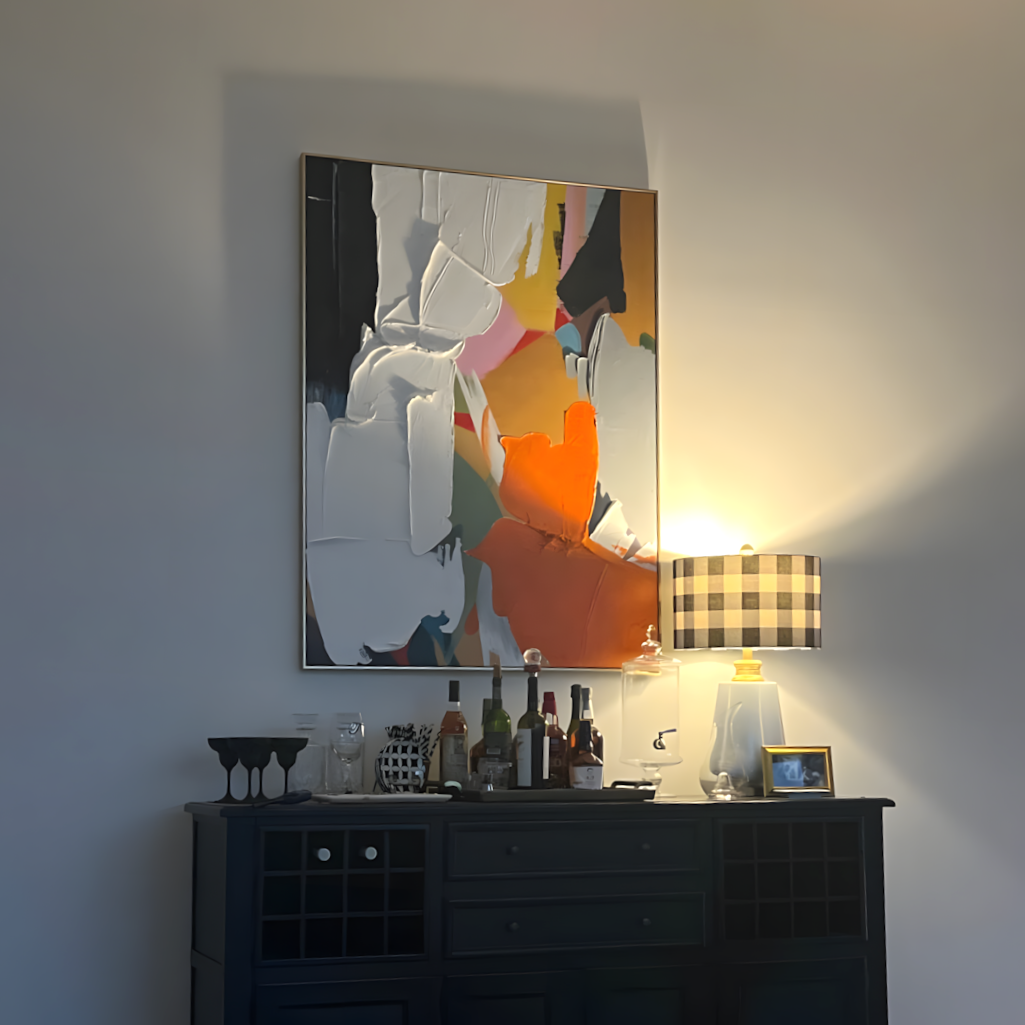 An abstract canvas painting with bold brushstrokes in orange, white, black, gray, and pink, displayed on a wall above a dark wooden console table.