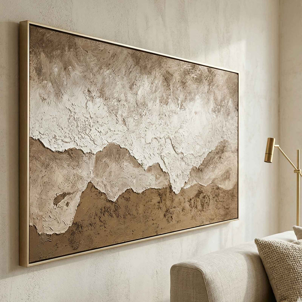 Large horizontal neutral landscape canvas artwork beautifully framed and hung above a modern rustic living room sofa.